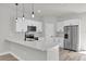 Bright kitchen with stainless steel appliances, white cabinetry, quartz countertops and island with pendant lighting at 13971 Sw 46Th Ter, Ocala, FL 34473