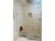 The shower is clad in floor-to-ceiling tile with a rain shower head and recessed shelving at 1414 Meadowlark St, Longwood, FL 32750