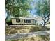 Well-kept single-story home featuring a blue front door, landscaping, and mature trees for shade at 1414 Meadowlark St, Longwood, FL 32750