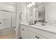 Well-lit bathroom with dual sinks, white cabinets, modern fixtures, and a bathtub with glass enclosure at 16018 Volterra Pt, Bella Collina, FL 34756