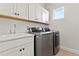 Modern laundry room with front load washer/dryer, basin sink, and white cabinets with matte hardware at 16018 Volterra Pt, Bella Collina, FL 34756