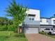 Modern two-story townhome featuring a brick driveway, a gray garage door, and a well-manicured front lawn at 1628 Little Wren Ln, Winter Park, FL 32792