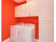 Laundry room featuring white washer and dryer, storage cabinets, and bright red walls at 1628 Little Wren Ln, Winter Park, FL 32792