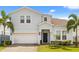 Charming two-story home with a two-car garage, well-manicured lawn, and decorative palm trees at 2036 Lelani Cir, Davenport, FL 33897
