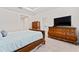 Bedroom featuring a wooden bed frame, matching dresser, and a view to an ensuite bath, creating a functional and comfortable space at 2214 Centerra Loop, Kissimmee, FL 34741