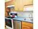 Efficient kitchen with wood cabinets, electric stove, and stainless steel dishwasher for modern convenience at 240 Windmeadows St # 240, Altamonte Springs, FL 32701