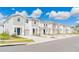 Row of charming townhomes with neutral paint, attached garages, landscaping, and blue sky with clouds at 2413 Brook Marsh Loop, Kissimmee, FL 34747