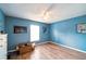 Bedroom with wood-look flooring, a ceiling fan, natural light, and painted in a bold blue color at 252 Elgin Blvd, Davenport, FL 33897