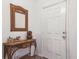 Inviting entryway with a white door, wooden console table, decorated with a wicker mirror and decorative vase at 252 Elgin Blvd, Davenport, FL 33897