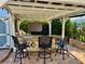 Elegant outdoor kitchen featuring a bar with seating, granite countertops, and an overhead pergola with lighting at 3067 Ne 102Nd Avenue Rd, Silver Springs, FL 34488