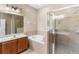 Bright bathroom with a soaking tub, glass-enclosed shower, and a wood vanity at 4027 Sunrise Ridge Blvd, Groveland, FL 34736