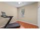 Bright bedroom featuring hardwood floors, a ceiling fan, and a Peloton exercise machine at 4027 Sunrise Ridge Blvd, Groveland, FL 34736