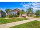 Charming single-story home featuring a well-manicured lawn, tropical landscaping, and brick accents under a blue sky at 4027 Sunrise Ridge Blvd, Groveland, FL 34736