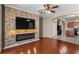 Living room featuring a stone accent wall, fireplace, floating shelves, and hardwood floors open to the kitchen at 4027 Sunrise Ridge Blvd, Groveland, FL 34736