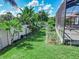 Lush backyard featuring tropical plants, a vegetable garden, a white fence, and a screened patio area at 543 Auburn Hill Blvd, Auburndale, FL 33823