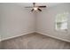 This carpeted bedroom has neutral walls, a ceiling fan, and a window to let the light in at 543 Auburn Hill Blvd, Auburndale, FL 33823