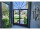 The entryway features a black screen door, a decorated wall, and a view of the front yard at 543 Auburn Hill Blvd, Auburndale, FL 33823