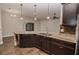 Kitchen with dark cabinets, granite countertops, stainless dishwasher, and pendant lights, showcasing a functional design at 543 Auburn Hill Blvd, Auburndale, FL 33823