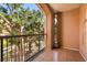 This is a view of a balcony with a black metal railing, tile flooring, and lush landscaping at 5524 Metrowest Blvd # 210, Orlando, FL 32811