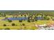 Picturesque aerial view of the community golf course featuring a pond, clubhouse, and lush green fairways at 6273 Toronja Dr, Indian Lake Estates, FL 33855