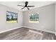 Bright bedroom with wood-look floors, a ceiling fan, and two windows overlooking the yard at 6273 Toronja Dr, Indian Lake Estates, FL 33855