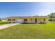 Charming single-story home featuring a well-manicured lawn, attached garage, and covered parking space at 6273 Toronja Dr, Indian Lake Estates, FL 33855