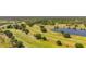 Picturesque aerial view of golfers enjoying a scenic golf course alongside a serene lake at 6273 Toronja Dr, Indian Lake Estates, FL 33855
