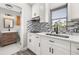 Bright kitchen showcasing white cabinets, mosaic backsplash, and stainless steel sink at 6273 Toronja Dr, Indian Lake Estates, FL 33855