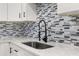 Close-up of a modern kitchen sink with a stylish faucet and mosaic tile backsplash at 6273 Toronja Dr, Indian Lake Estates, FL 33855