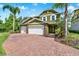 Inviting two-story home featuring a three-car garage, manicured landscaping, and a brick paver driveway at 732 Wildmere Village Cv, Longwood, FL 32750