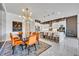 Elegant dining area with a modern chandelier, orange chairs, and open view to the kitchen and breakfast bar seating at 7613 Toscana Blvd, Orlando, FL 32819