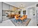 Modern dining room featuring a black table, bright orange chairs, a stylish chandelier, and large mirror reflecting the kitchen at 7613 Toscana Blvd, Orlando, FL 32819