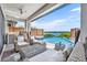 Covered outdoor living area featuring wicker furniture, a built-in kitchen, and a stunning view of the pool and lake at 7613 Toscana Blvd, Orlando, FL 32819