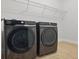 A modern laundry room featuring front loading washer and dryer units and an above the appliance storage shelf at 8972 Sonoma Coast Dr, Winter Garden, FL 34787
