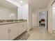 Well-lit bathroom with dual sinks, white cabinets, and tile flooring, connecting to the bedroom for convenience at 9084 Sommerset Hills Dr, Davenport, FL 33896