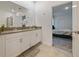 Bathroom with double vanity sinks, white cabinetry, and a view of the bedroom, offering convenience and style at 9084 Sommerset Hills Dr, Davenport, FL 33896