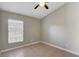 A minimalist bedroom featuring a ceiling fan, neutral paint, and a window providing natural light at 9447 Dearmont Ave, Orlando, FL 32825