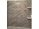 This bathroom shower has marble-look tiles and storage shelves for toiletries at 1180 Baton Dr, Deltona, FL 32725