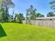 Backyard featuring lush green grass and surrounded by a wooden fence and mature trees at 1314 Victory Palm Dr, Edgewater, FL 32132