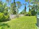 The backyard features lush grass that is surrounded by a wooden fence and mature trees at 1314 Victory Palm Dr, Edgewater, FL 32132