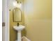 Half bathroom featuring a pedestal sink, an arched mirror, and simple, stylish lighting fixtures at 1354 Riley Cir, Deland, FL 32724
