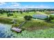 Aerial view showcasing a tennis court and fishing pier surrounded by lush greenery and a pond at 14738 Porter Rd, Winter Garden, FL 34787
