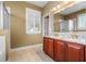 Bathroom featuring a double vanity with granite countertop, wood cabinets, and a large window with plantation shutters at 14738 Porter Rd, Winter Garden, FL 34787