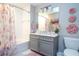 Bright bathroom featuring a gray vanity, floral shower curtain, and decorative pink flower wall art at 16300 County Road 455 # 606, Montverde, FL 34756