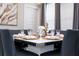 Beautifully staged dining room with seating for six, elegant tableware and marble accent artwork at 16300 County Road 455 # 606, Montverde, FL 34756