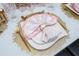 Beautifully set dining table featuring elegant gold cutlery, ornate placemats, and a stylishly folded napkin on pristine white plates at 16300 County Road 455 # 606, Montverde, FL 34756
