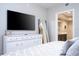 Modern bedroom with TV, dresser and leaning mirror leading to ensuite bath at 16300 County Road 455 # 606, Montverde, FL 34756
