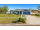 Well-manicured front yard of a charming single-story home with a blue exterior, garage, and decorative accents at 20321 Majestic St, Orlando, FL 32833