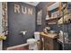 Charming powder room with rustic vanity, vessel sink, and unique 'RUN' artwork on a dark accent wall at 204 Green Lake Cir, Longwood, FL 32779