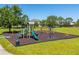 Community playground featuring slides, climbing structures, and swings on a mulch surface with green grass and trees at 2340 Hinsdale Dr, Kissimmee, FL 34741
